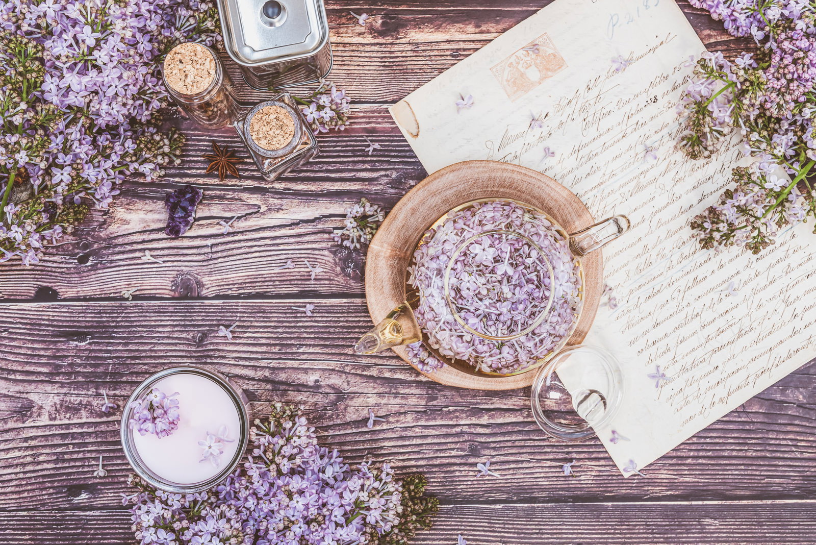木製テーブルに置かれたライラックの花とハーブティーのセット