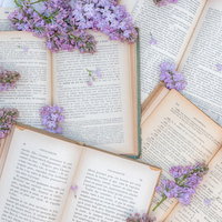 ばら撒かれた洋書とライラックの花が並ぶアンティークな読書空間の写真