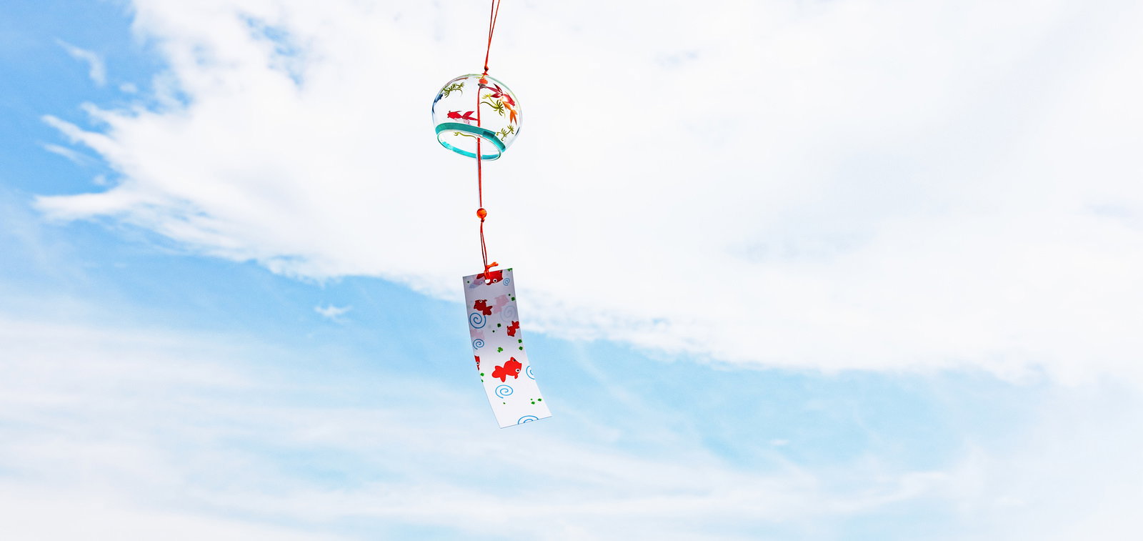 青空を背景に赤い紐で吊るされた、花柄の風鈴と短冊