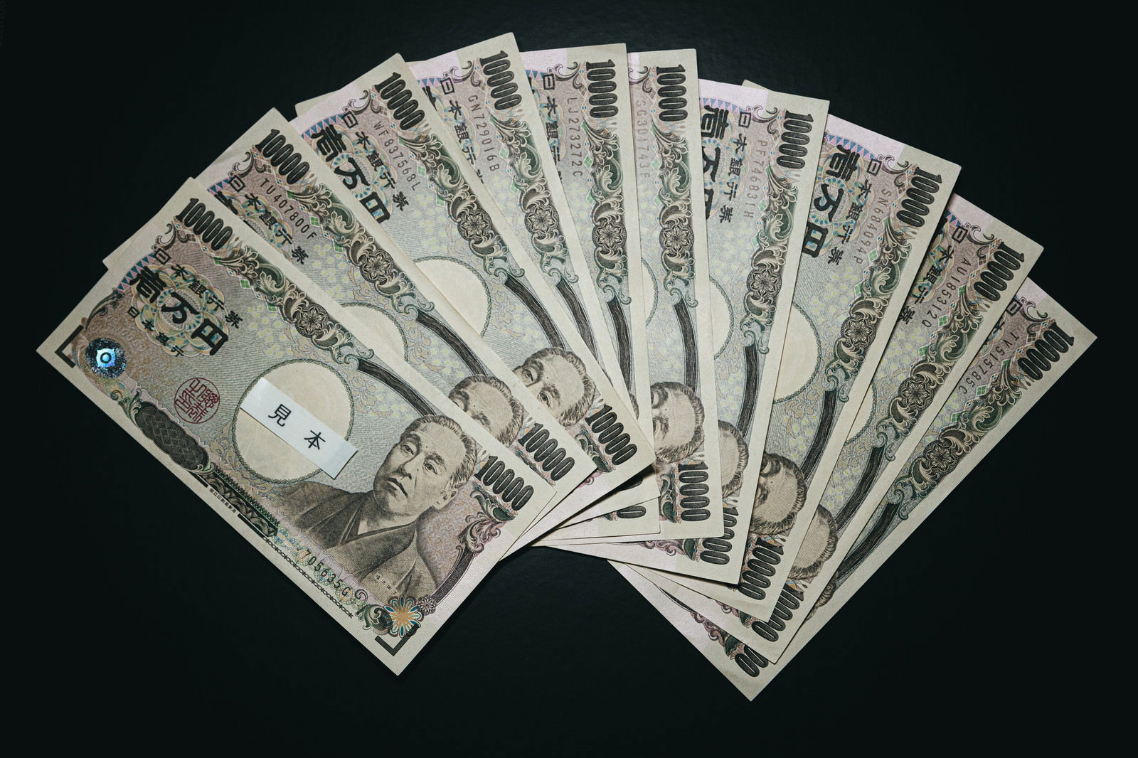 黒い背景に扇状に広げられた複数枚の一万円札