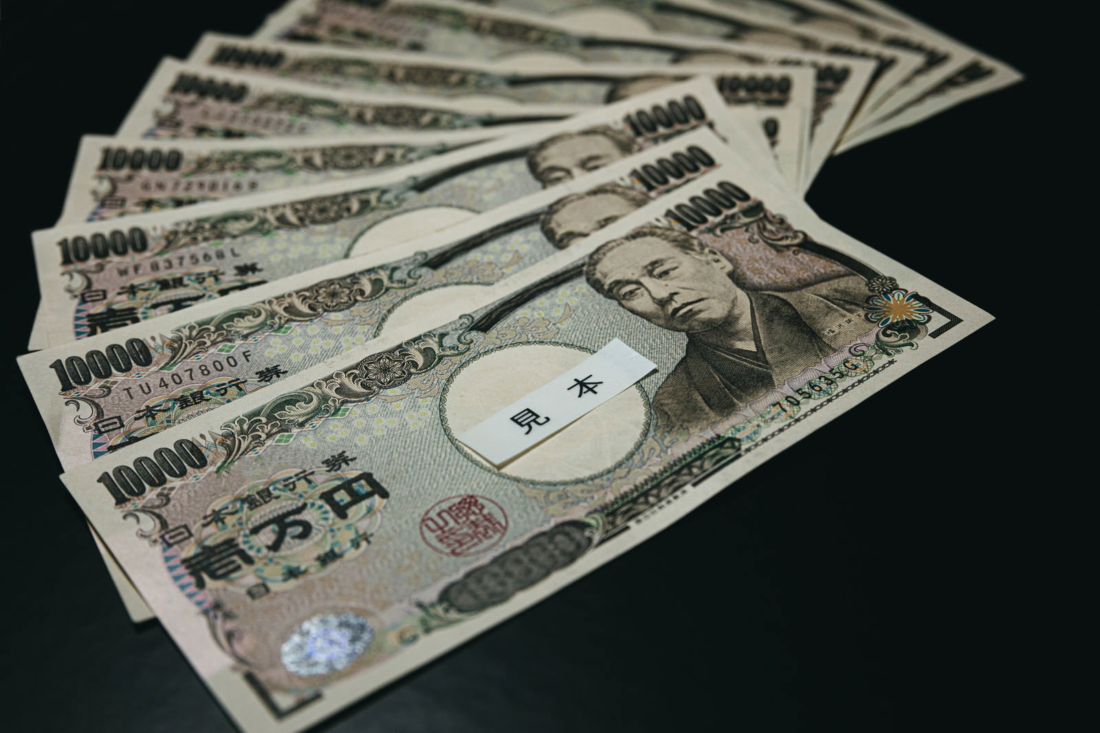 白い背景に扇状に広げて配置された複数枚の一万円札