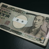 壱万円札10枚を重ねて配置した見本スタンプ付き札束の写真