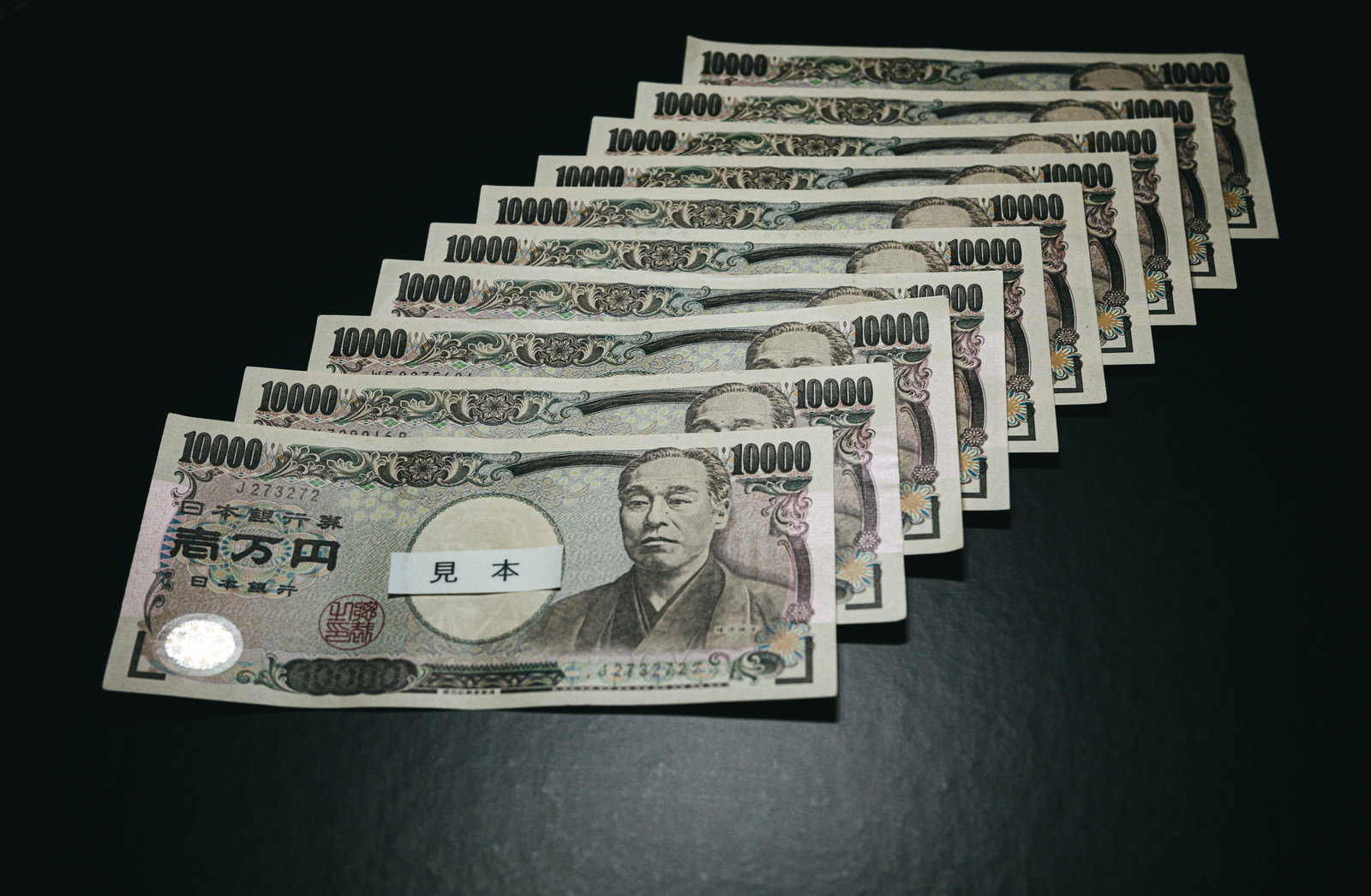 黒い背景に整然と並べられた10万円分の一万円札