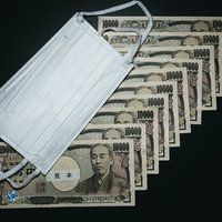 10万円の給付金とマスク2枚、一万円札10枚が扇状に広げられたの写真