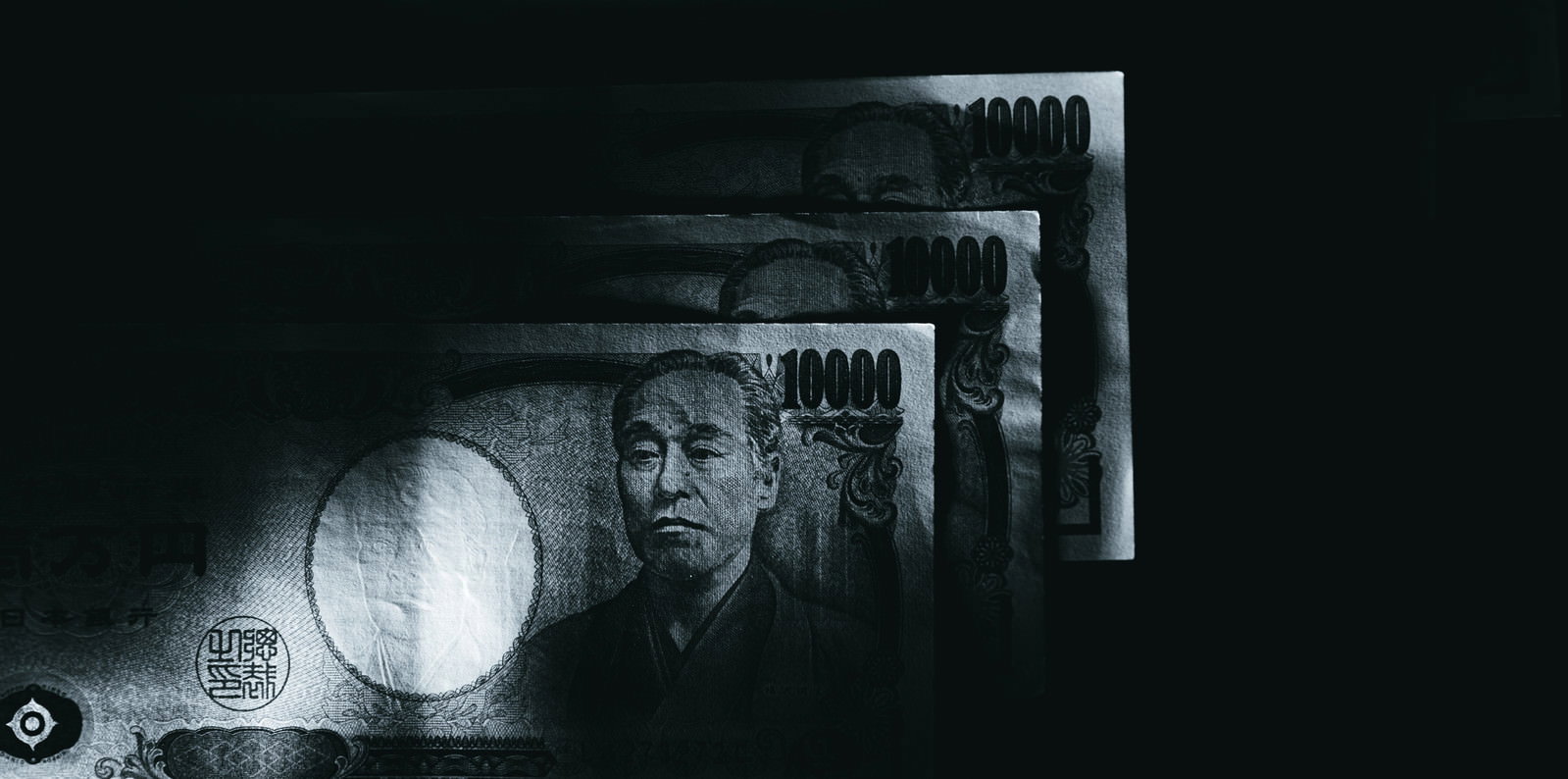 暗闇の中でライトに照らされて浮かび上がる一万円札