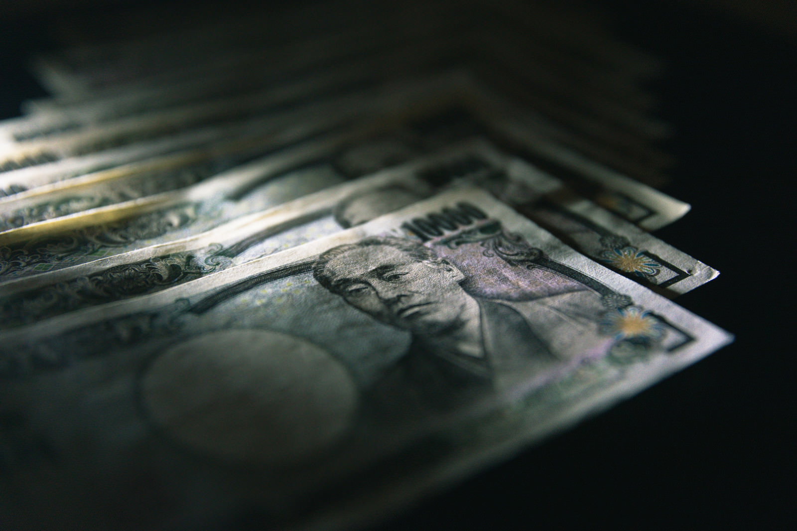 暗闇の中に散らばって重なり合う複数の一万円札