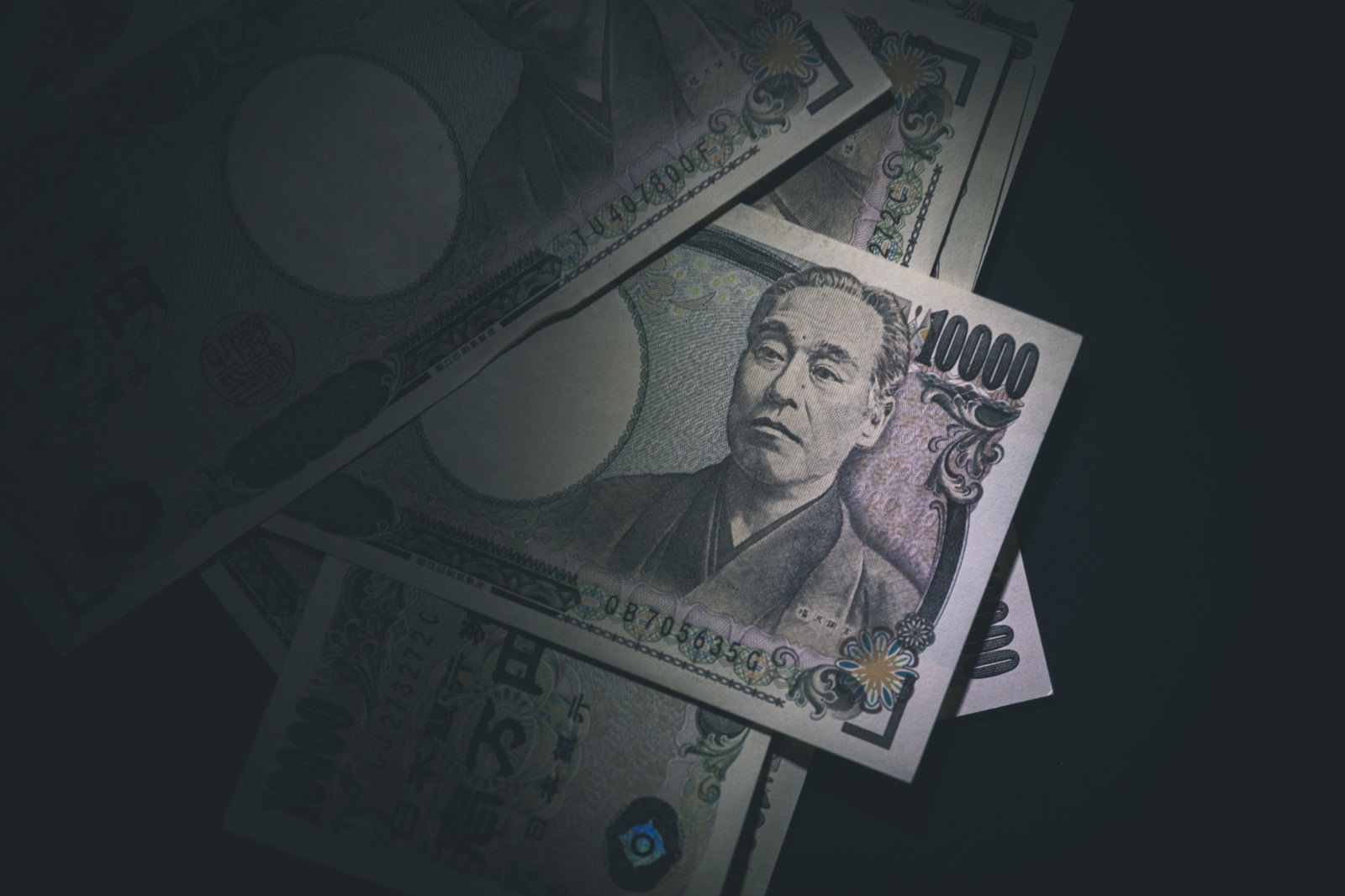 暗い背景に置かれた複数の一万円札