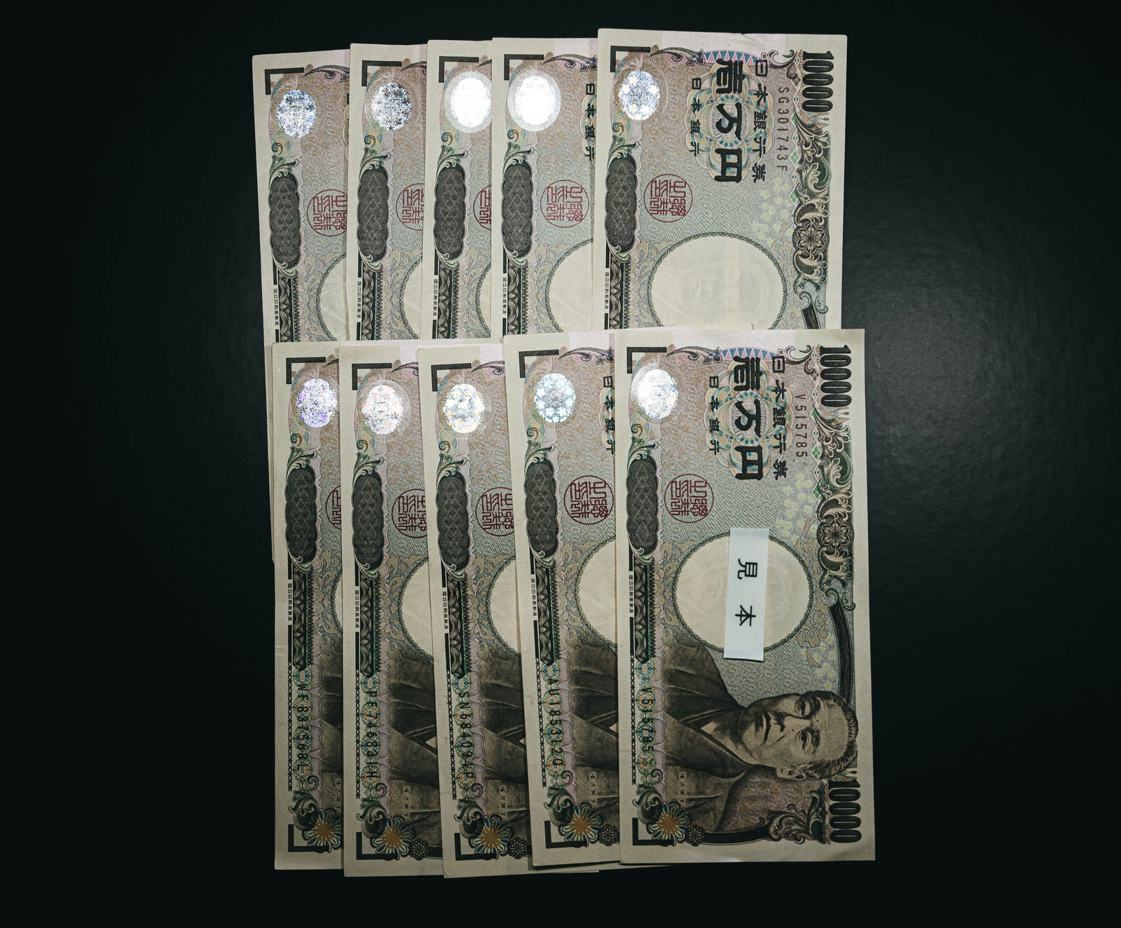 黒い背景に扇状に広げて配置された10万円分の一万円札