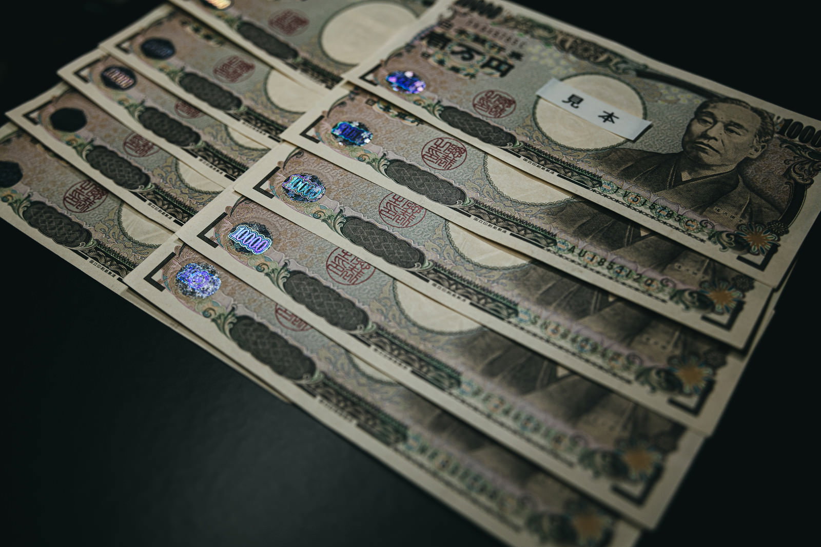 暗い背景の上に重ねて置かれた10万円分の一万円札