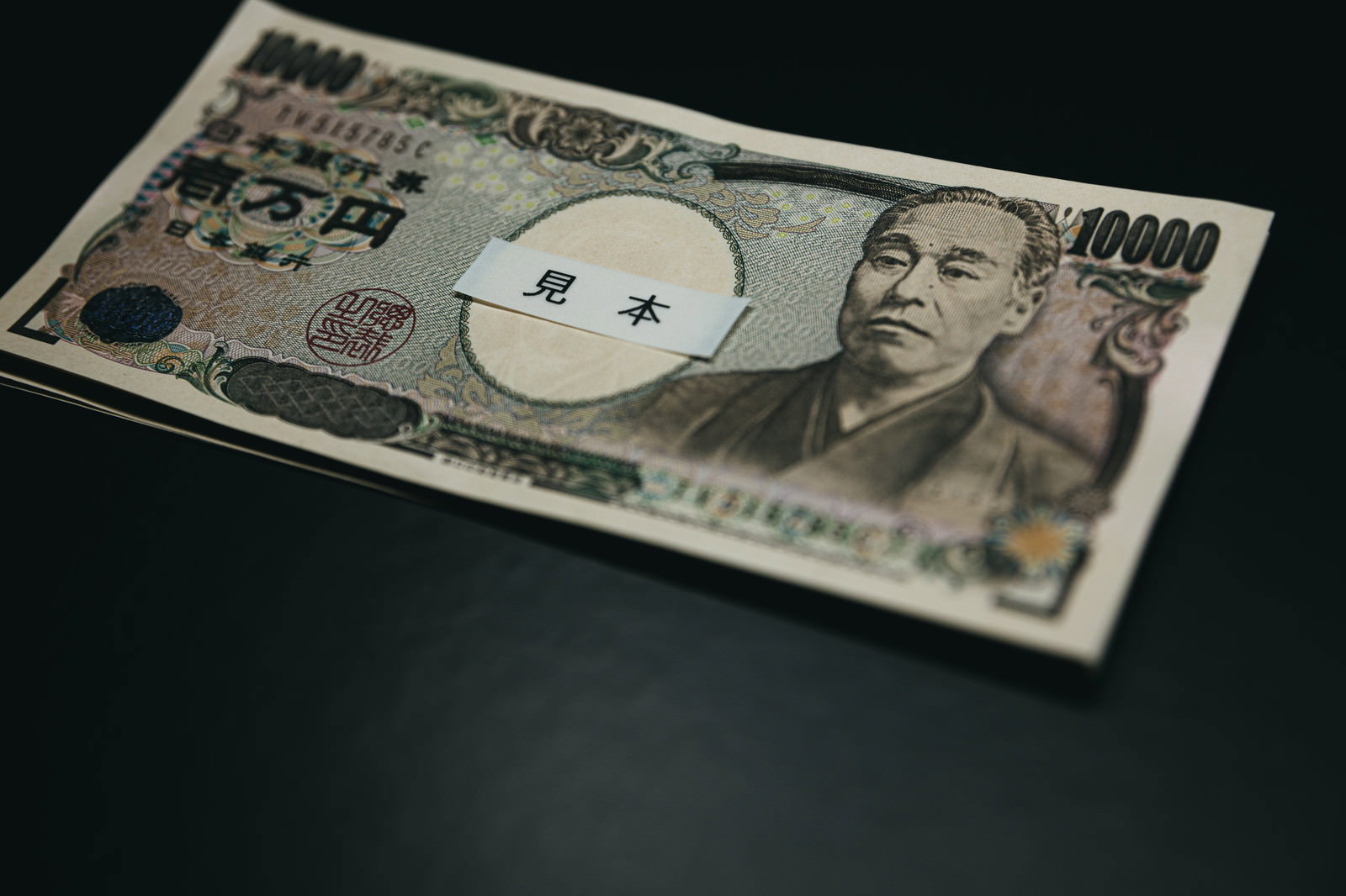 暗い背景に置かれた壱万円札（福沢諭吉の紙幣）