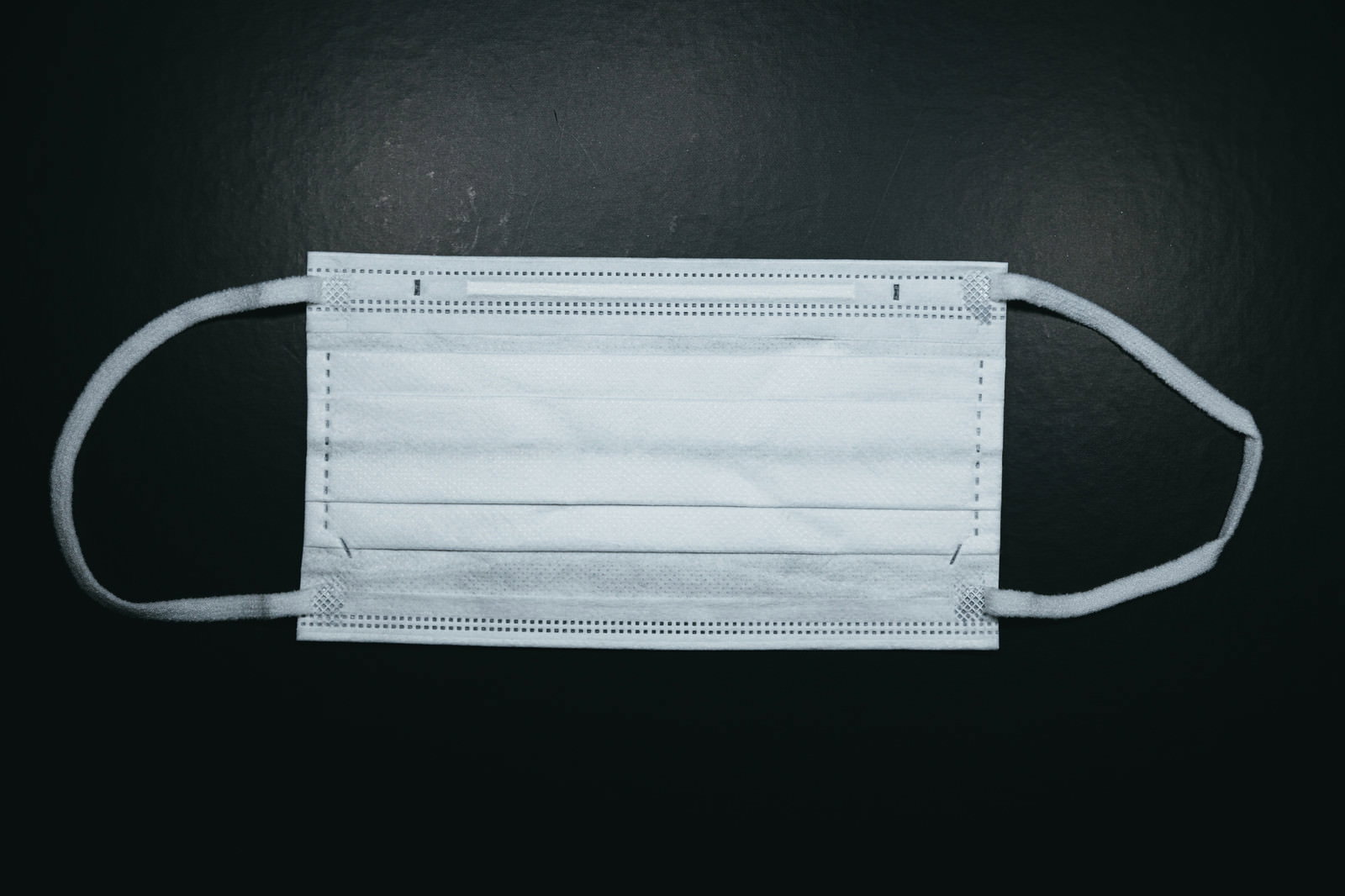 黒い背景に置かれた白い不織布の使い捨てマスク