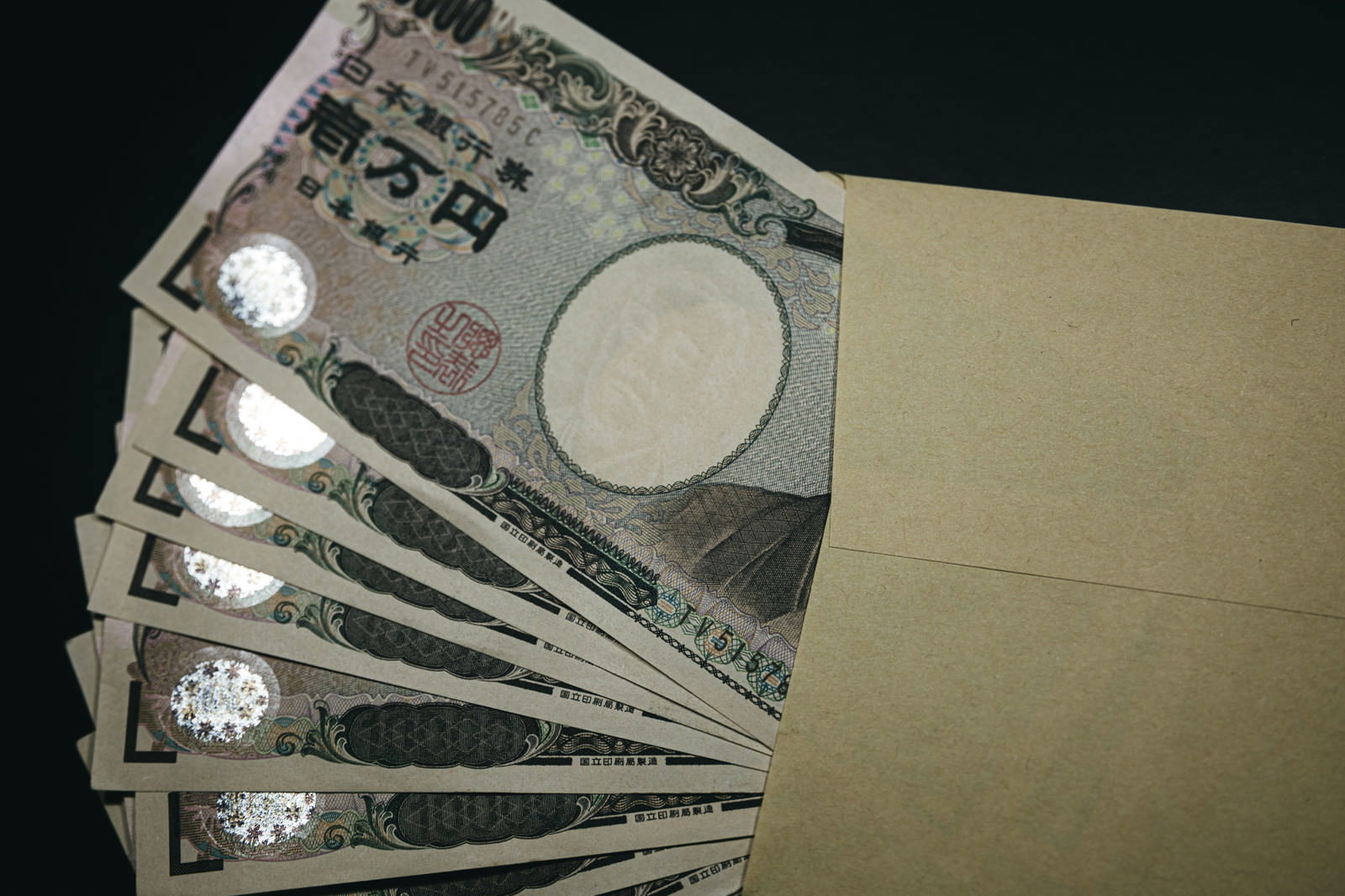 茶色の封筒から複数枚の一万円札が見えている様子