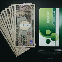 10万円と銀行の通帳と印鑑が並ぶ金銭管理のシーンの写真