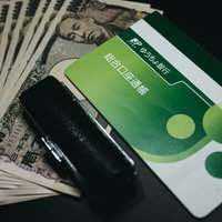 銀行の判子と通帳に置かれた引き出された10万円の写真