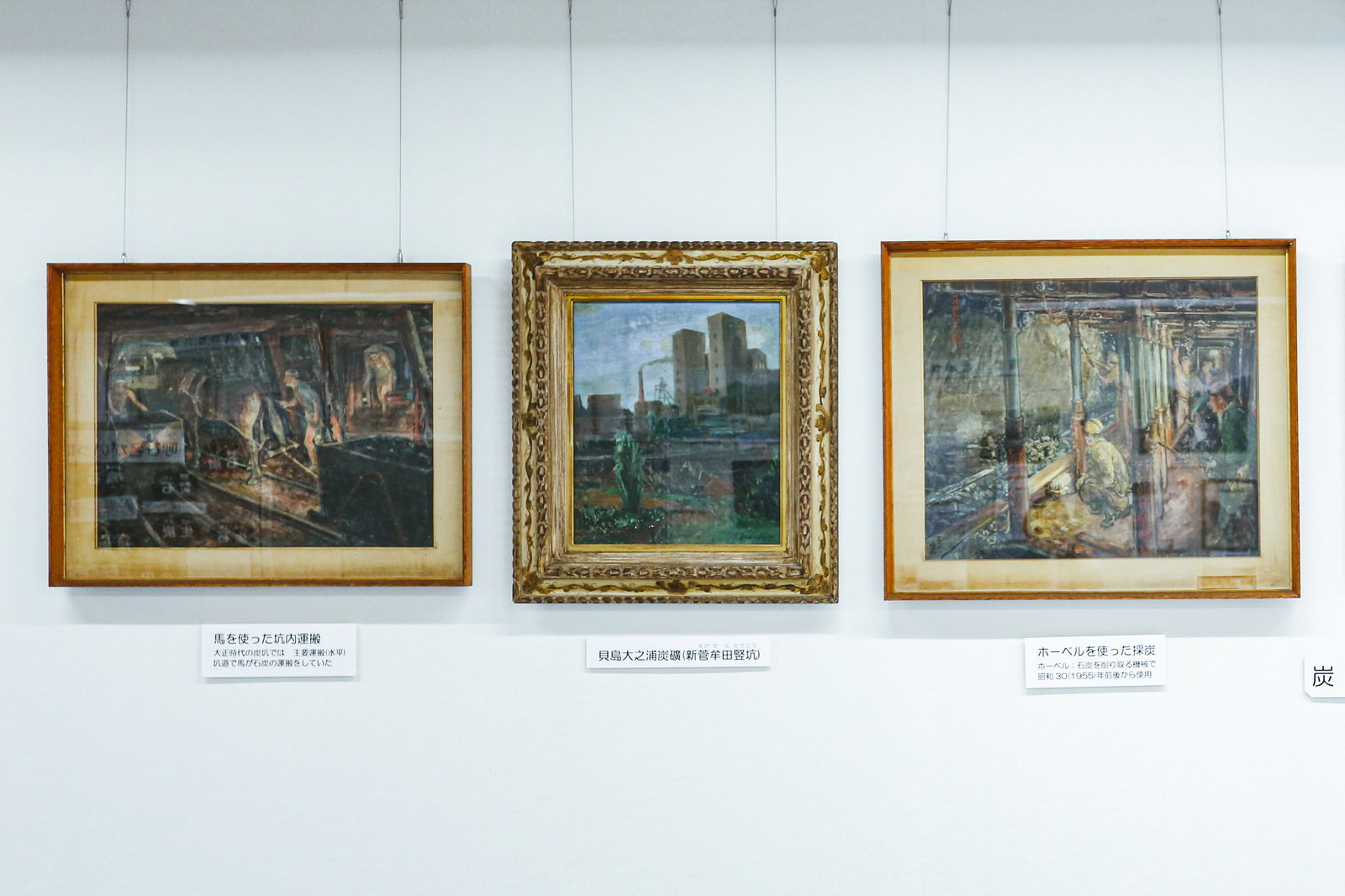 石炭記念館の壁に展示された金色の額縁に入った3枚の炭鉱絵画