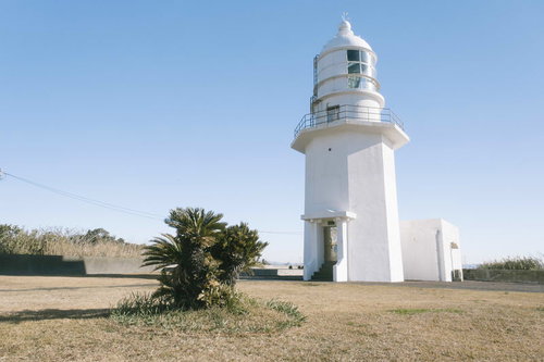 青空の下に立つ白い剣崎灯台と周辺の芝生広場