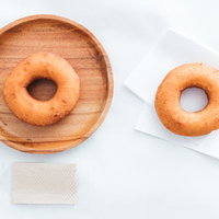 木の皿とテイクアウト用紙袋のドーナッツ2種類の比較の写真