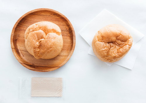 木製のお皿に盛られたシュークリーム2つ、カスタードクリーム入り