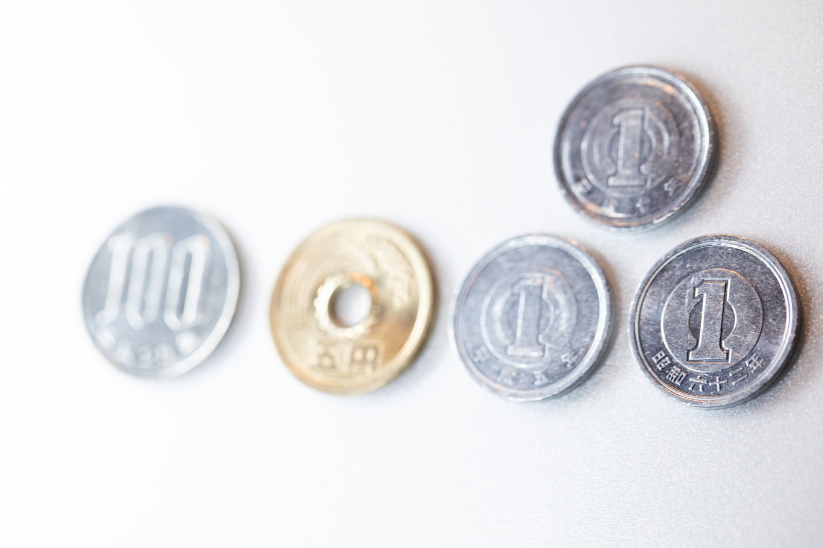 白い背景に置かれた百八円分の小銭（5円玉、10円玉、50円玉、100円玉）