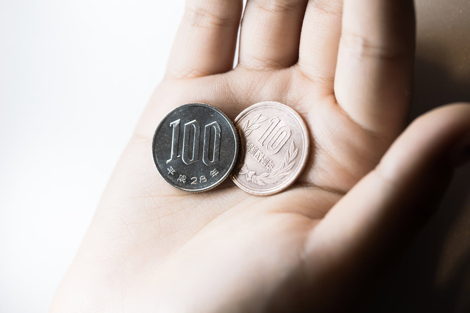 手のひらに載せられた100円硬貨と1円硬貨