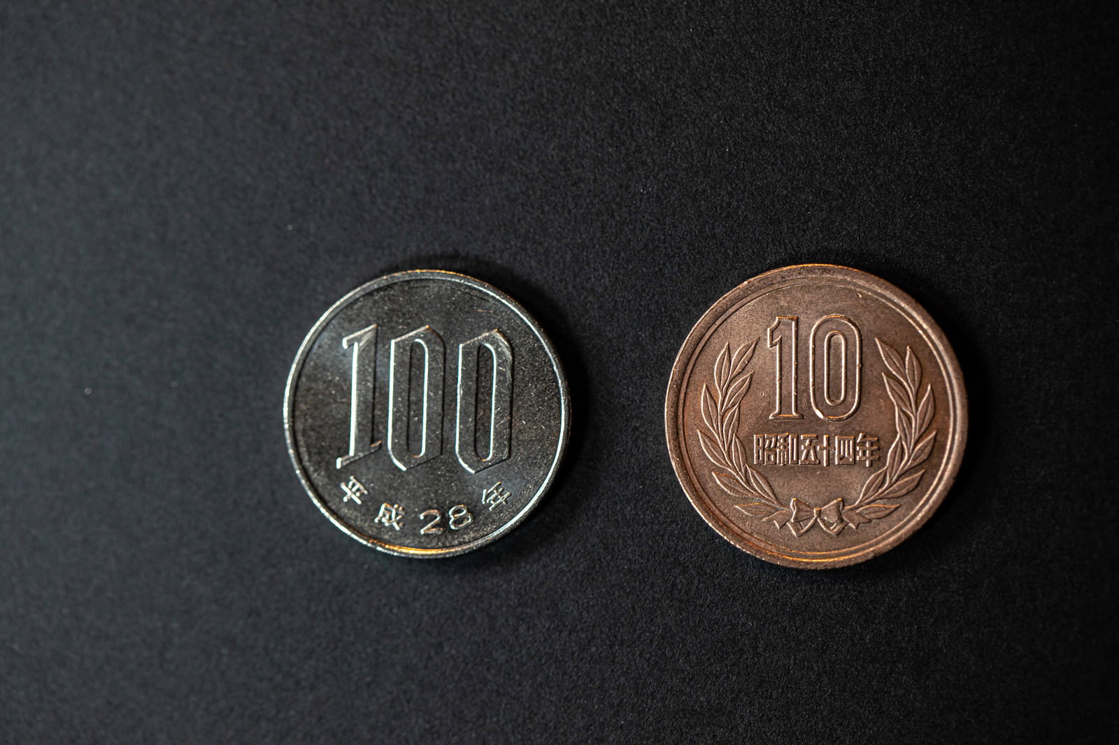 黒い背景に置かれた100円硬貨と10円硬貨