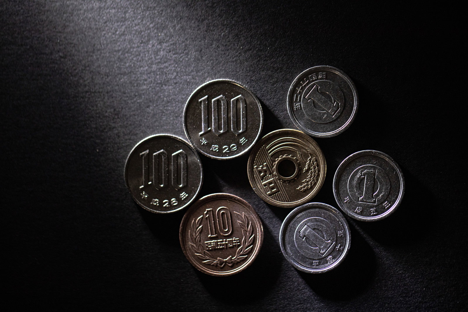 黒い表面に置かれた218円分の硬貨が円形に配置された小銭