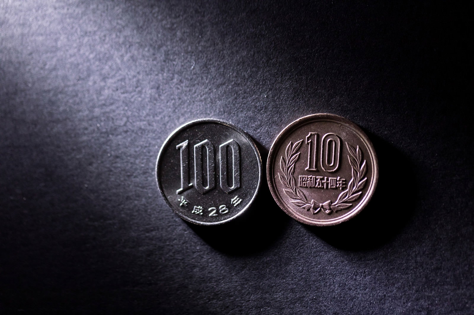 暗い背景に置かれた100円硬貨と10円硬貨