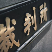 近づいて見た裁判所の銘板と看板 黒い石材に金色の文字の写真
