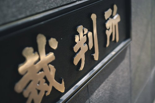 近づいて見た裁判所の銘板と看板 黒い石材に金色の文字