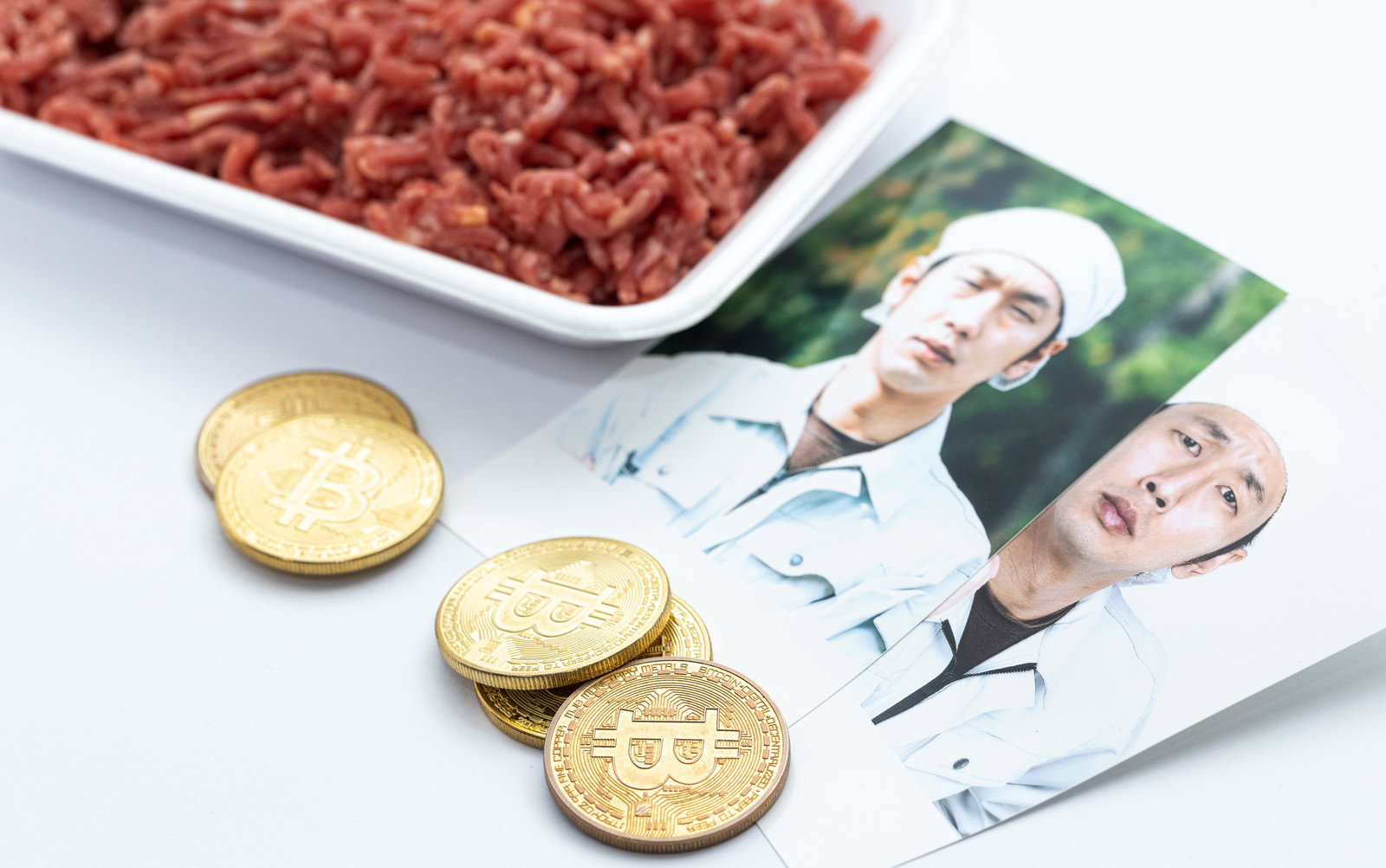 白い皿に盛られた挽肉と生産者の写真、ビットコインが一緒に配置された様子［モデル：大川竜弥］