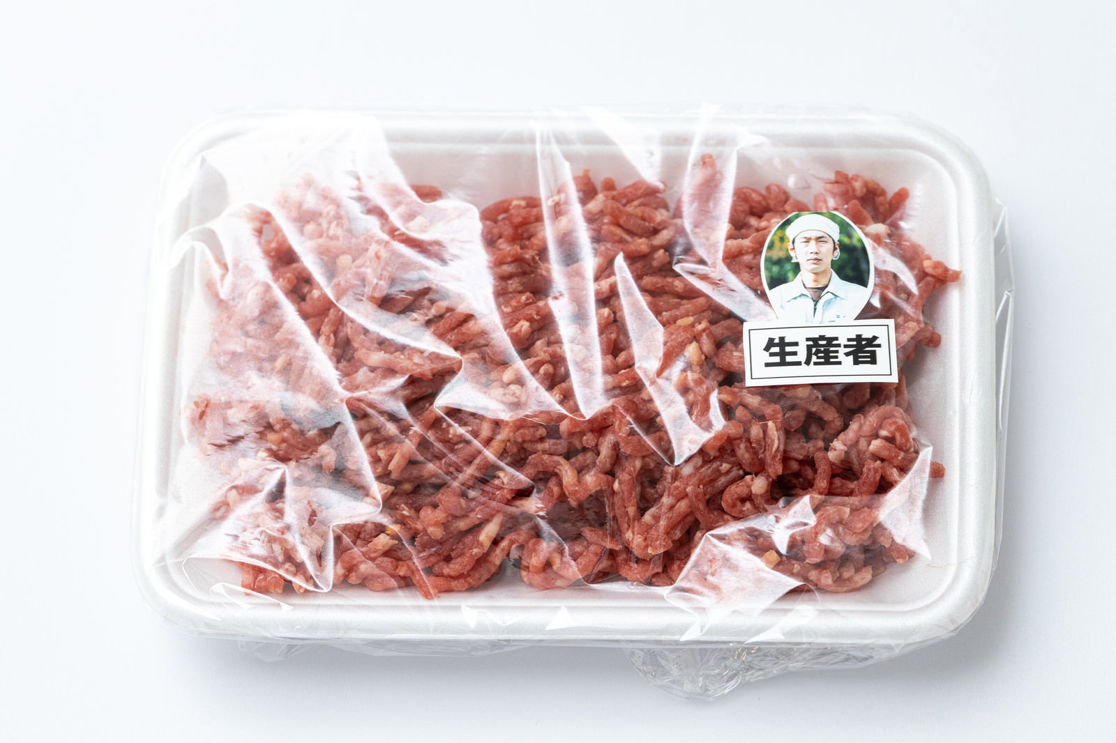 透明パックに入った赤身のひき肉とラベル［モデル：大川竜弥］