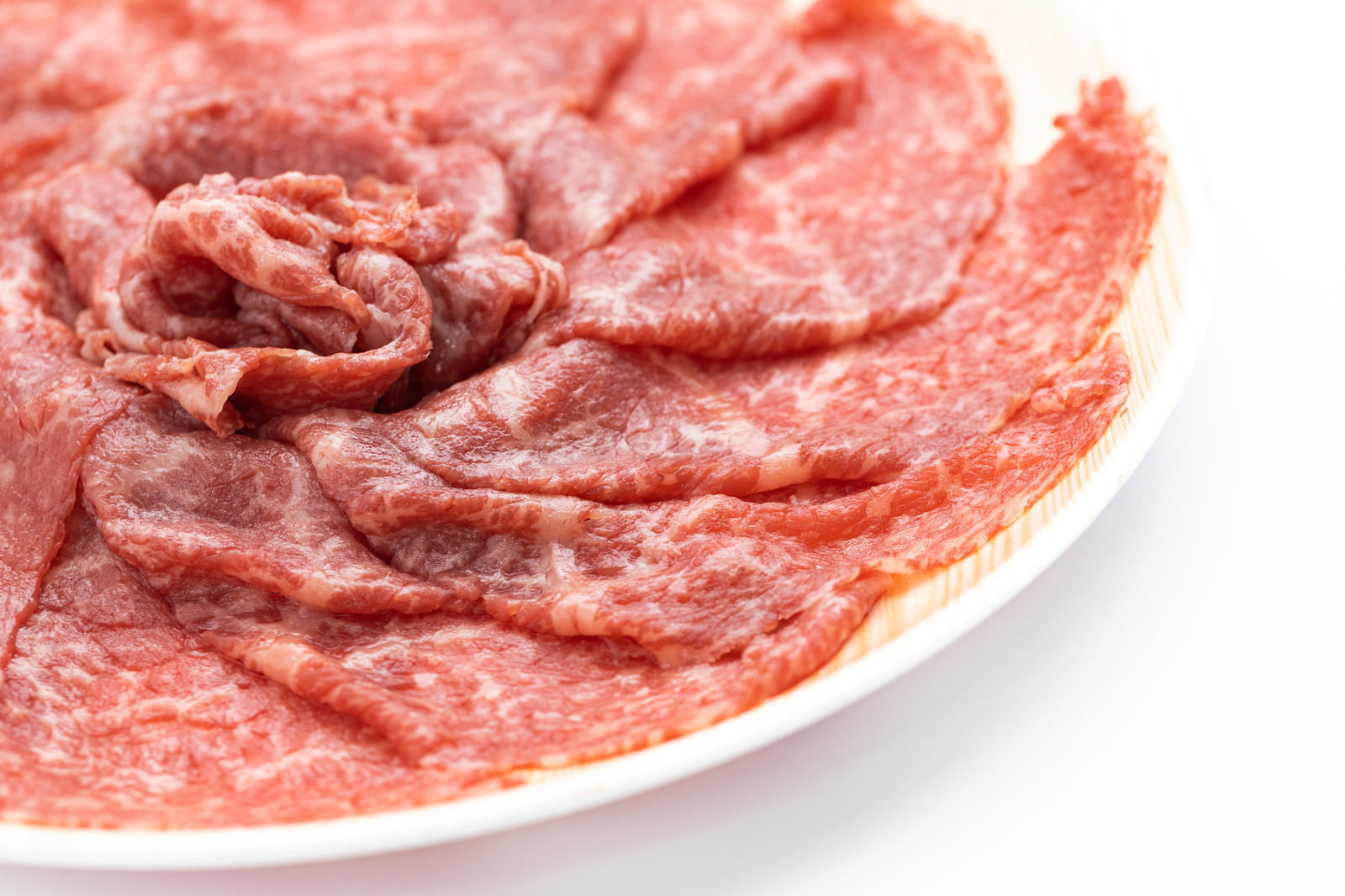 白い皿に赤身と霜降りの牛肉薄切りが重なって盛られている