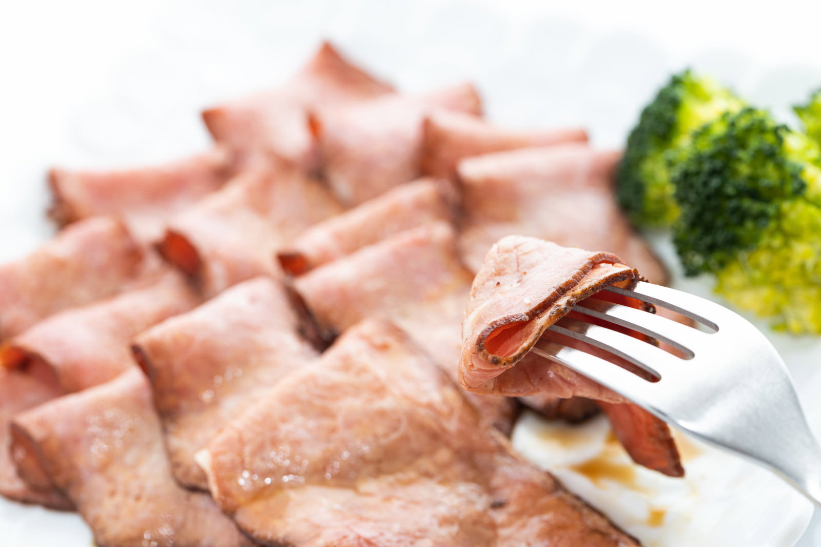 白いお皿に盛り付けられたローストビーフをフォークで食べている様子