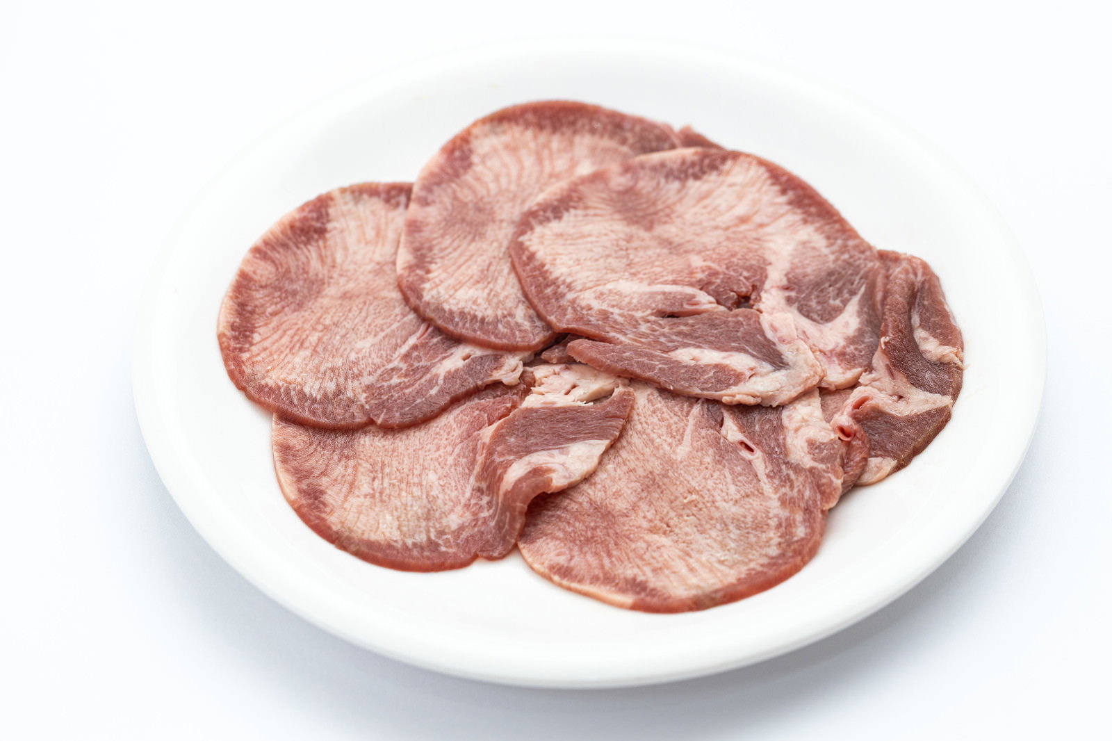 白い皿の上に薄くスライスされた牛タンが並べられている