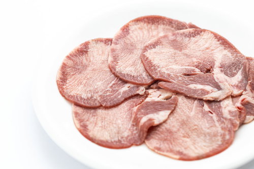 白い皿に盛り付けた一人前のタン塩、薄くスライスされた牛タン