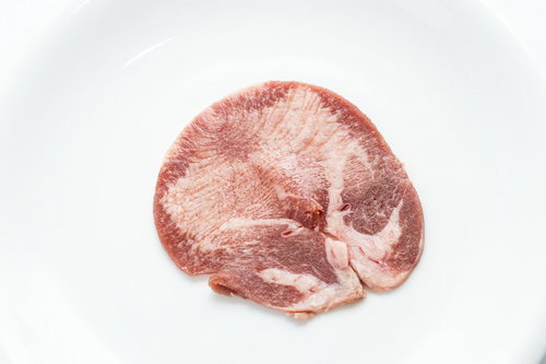 白い皿に盛られた新鮮な牛タン、焼肉用高級食材