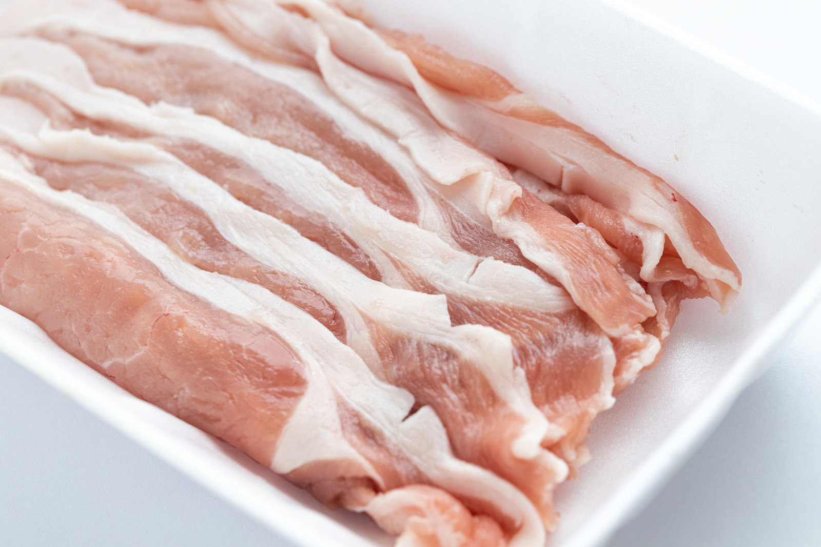 白い皿に整然と並べられたしゃぶしゃぶ用の薄切り豚ロース肉