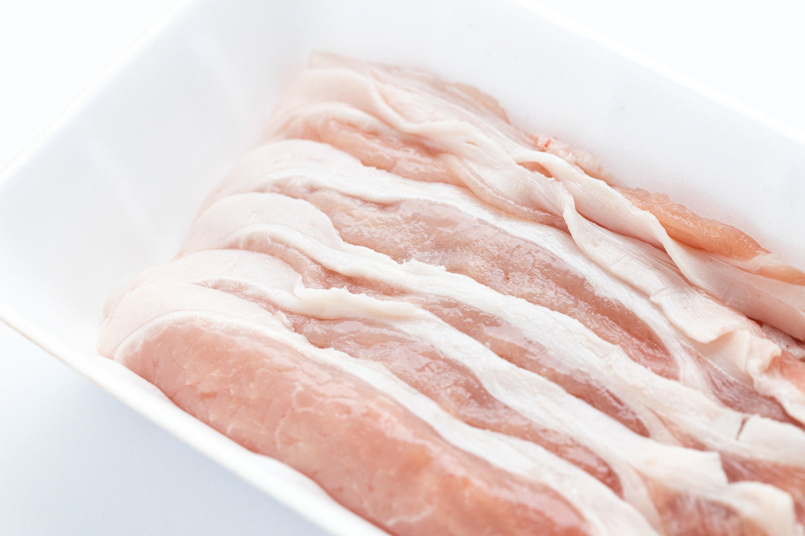 白いトレイに並べられた豚ロースのしゃぶしゃぶ用薄切り肉