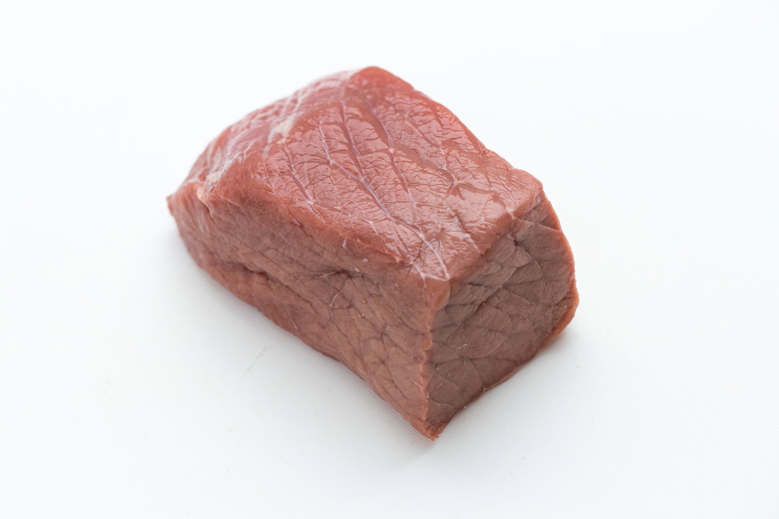 白い背景に置かれたブロック状の赤い牛肉の塊