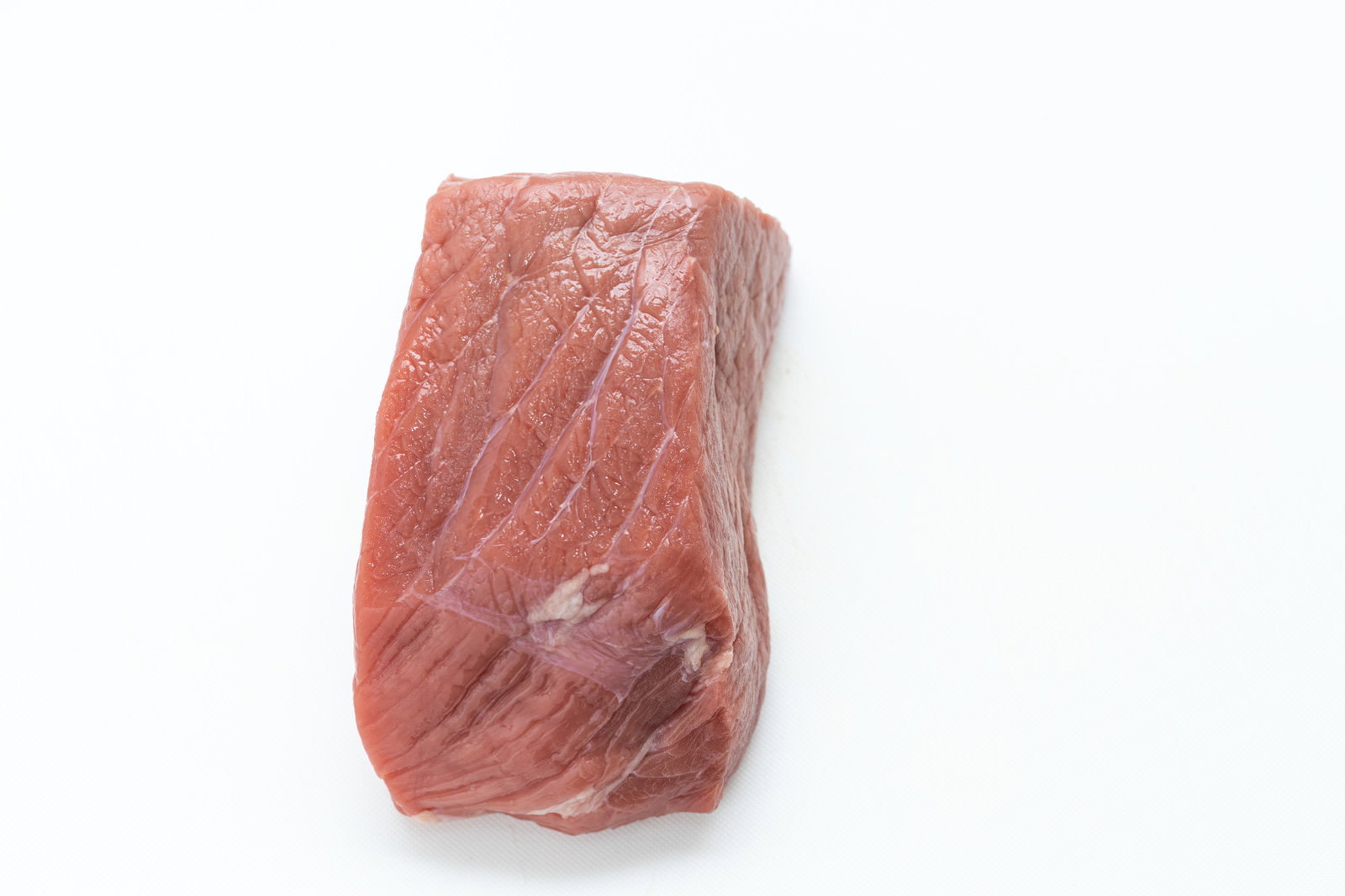 ラップに包まれた赤身のかたまりブロック肉を真上から撮影