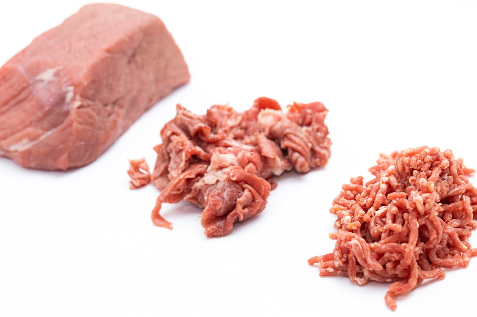 白い背景に置かれた牛肉のブロックとミンチ肉