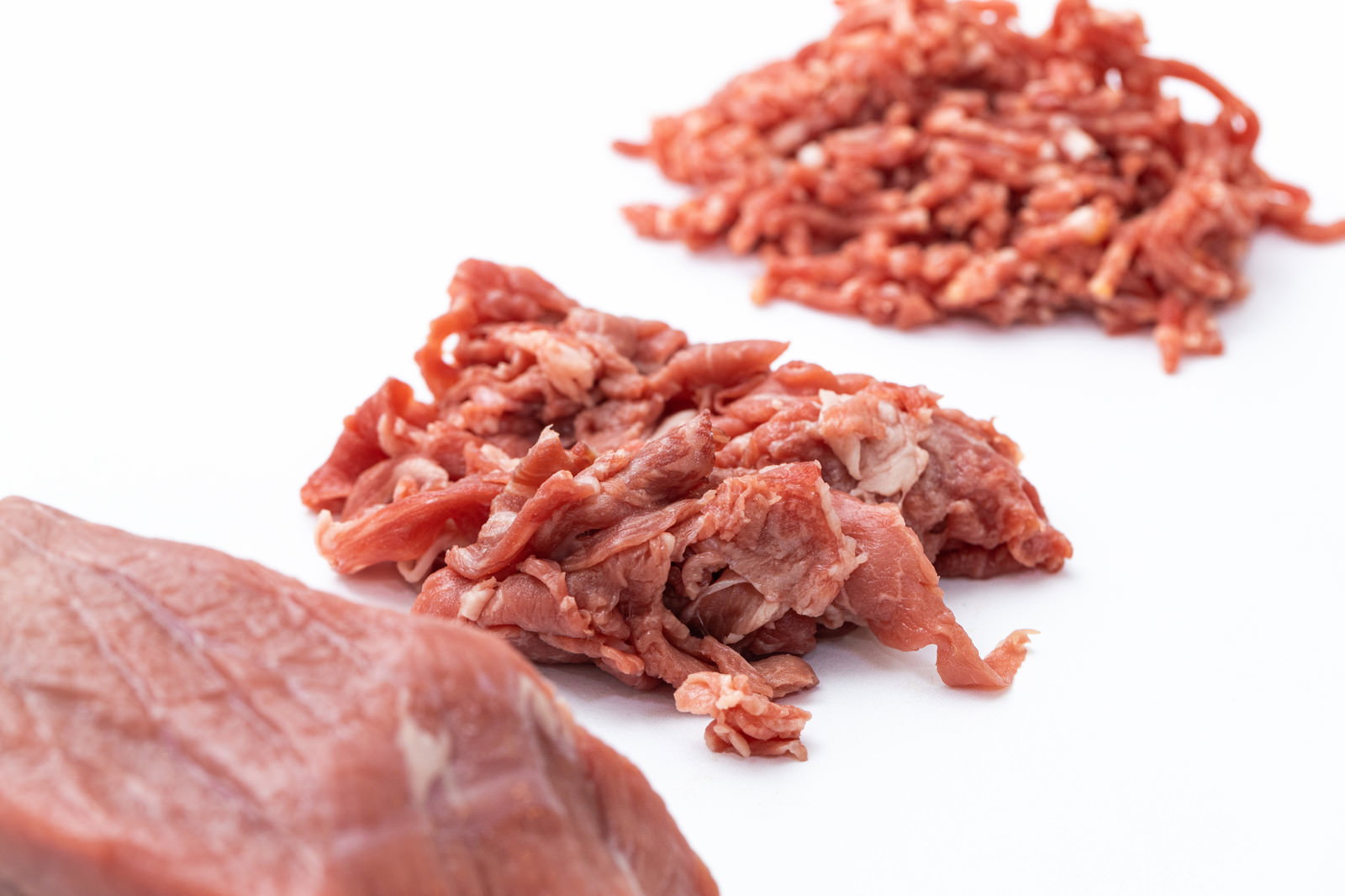 白い背景に置かれた牛肉のブロック肉、細切れ肉、ミンチ肉