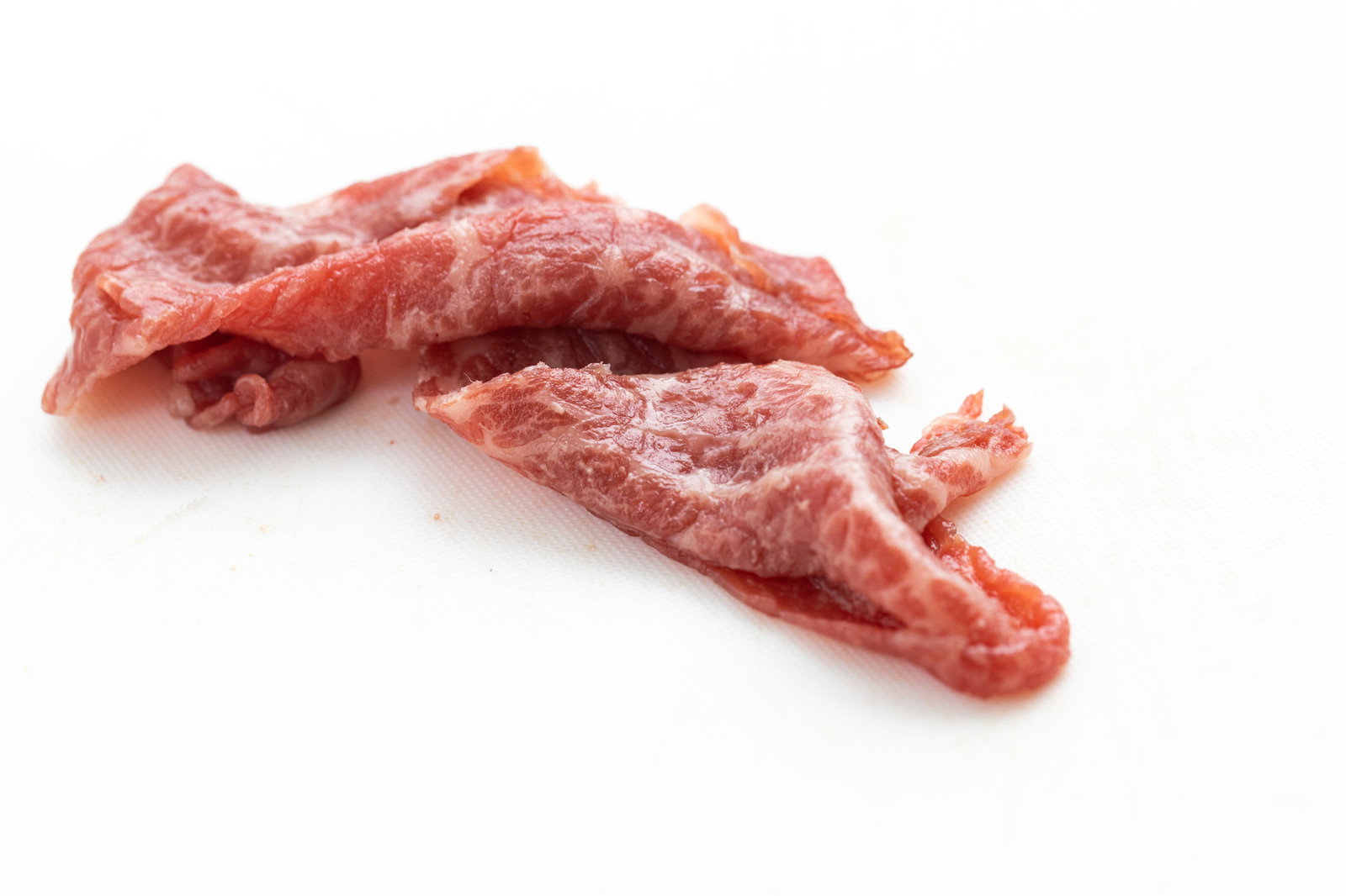 白い背景に置かれた赤身の牛肉の細切れ