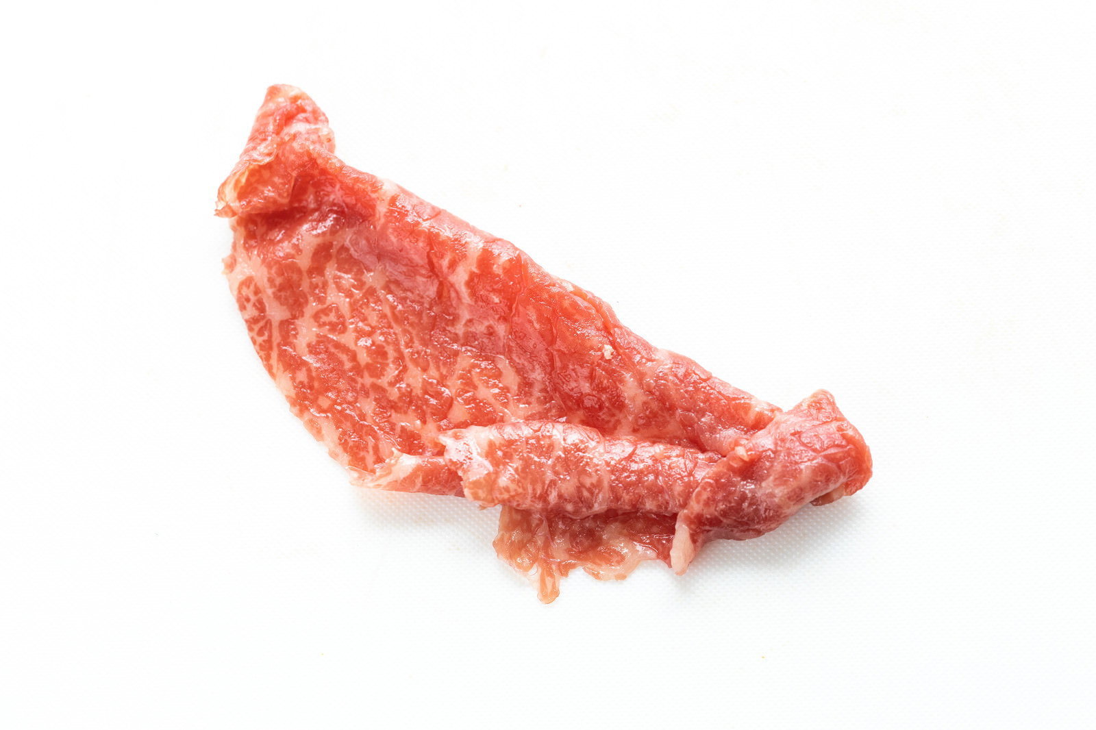 白い背景に置かれた霜降りの入った生牛肉