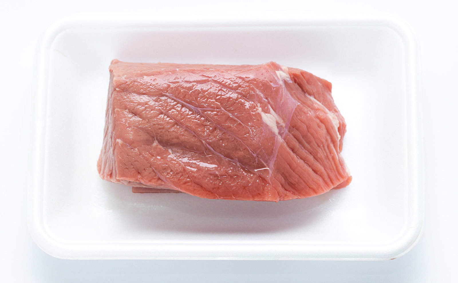 白いトレーの上に置かれた赤身の牛モモ肉ブロック