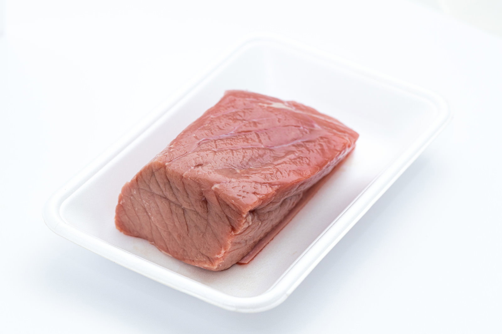 白い食品トレーの上に置かれた赤身の牛肉ブロック