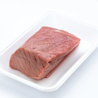 白いトレーに盛られた赤身の牛肉ブロック、低脂肪のもも肉の写真