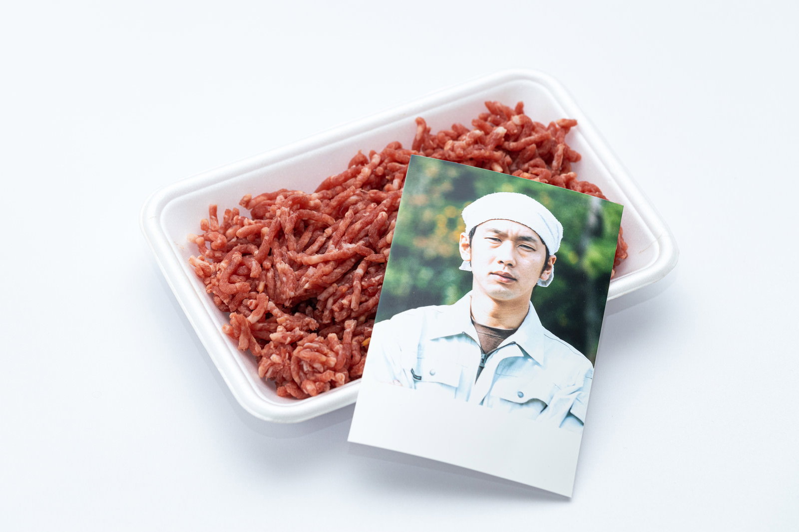 白いトレーに入った赤いミンチ肉と調理服姿の生産者の写真［モデル：大川竜弥］