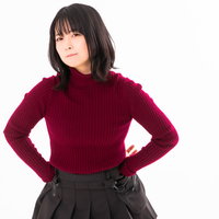 腰に手を置きふてくれる赤いセーターの女性の写真
