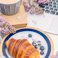 花で彩る朝食シーン、クロワッサンとノートパソコンの写真